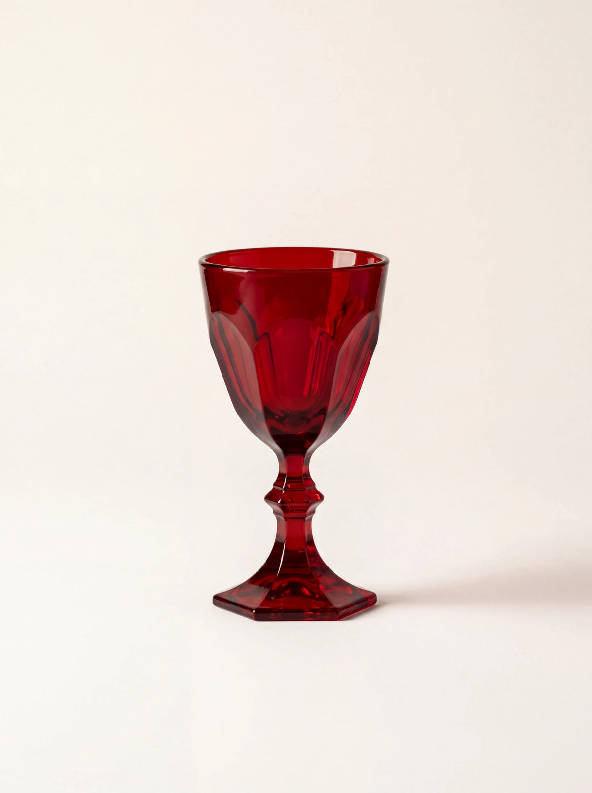 Stemmed red acrylic shot glass with a faceted bowl, central knop and hexagonal base