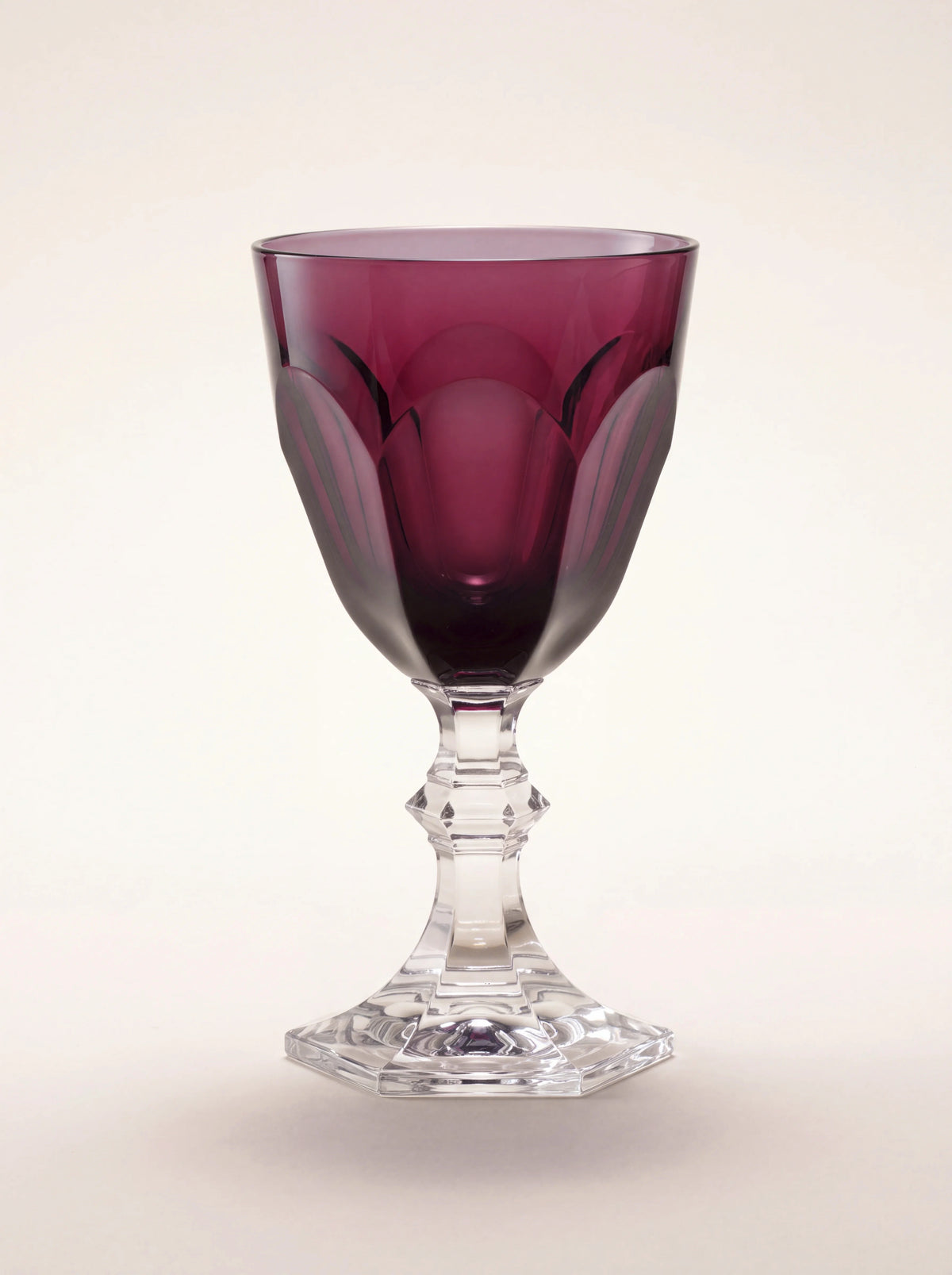 Acrylic water glass with a faceted ruby-red bowl and a clear geometric stem on a hexagonal base