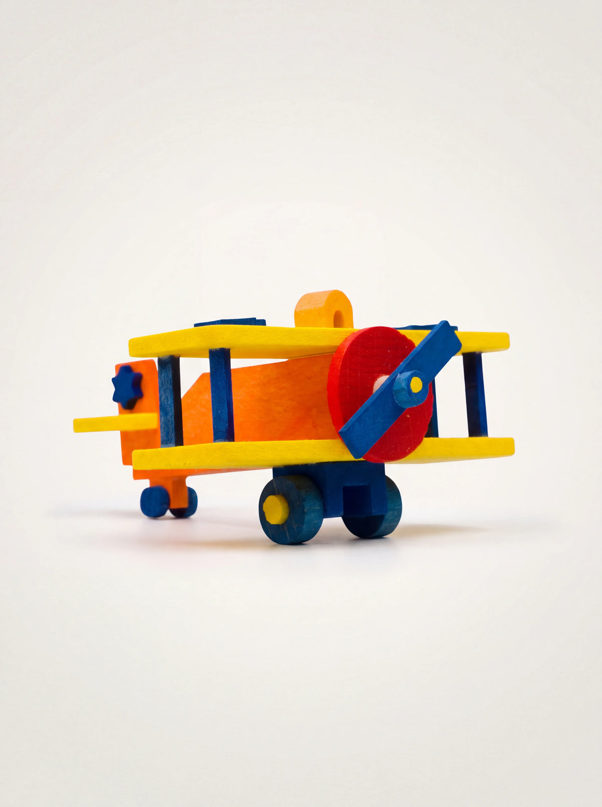 Maple wood biplane ornament with yellow wings, an orange fuselage, blue propeller and hanging eyelet