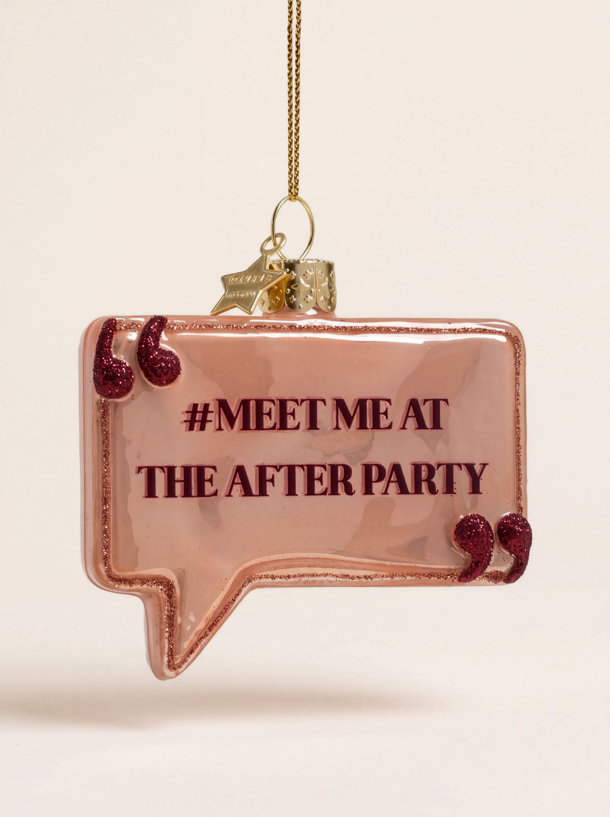 Speech bubble glass ornament in dusty pink reading #MEET ME AT THE AFTER PARTY with glitter quotation marks
