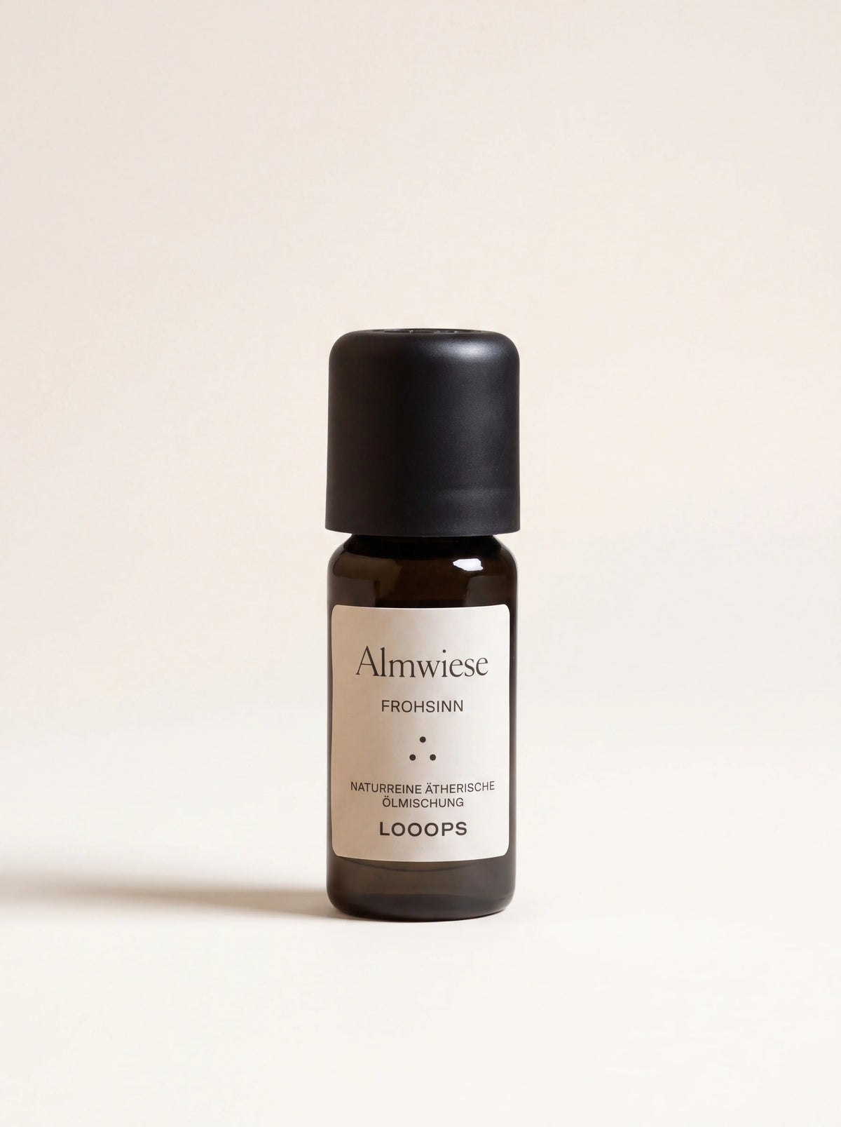 Amber glass dropper bottle of Almwiese essential oil with a matte black cap, labelled Almwiese Frohsinn