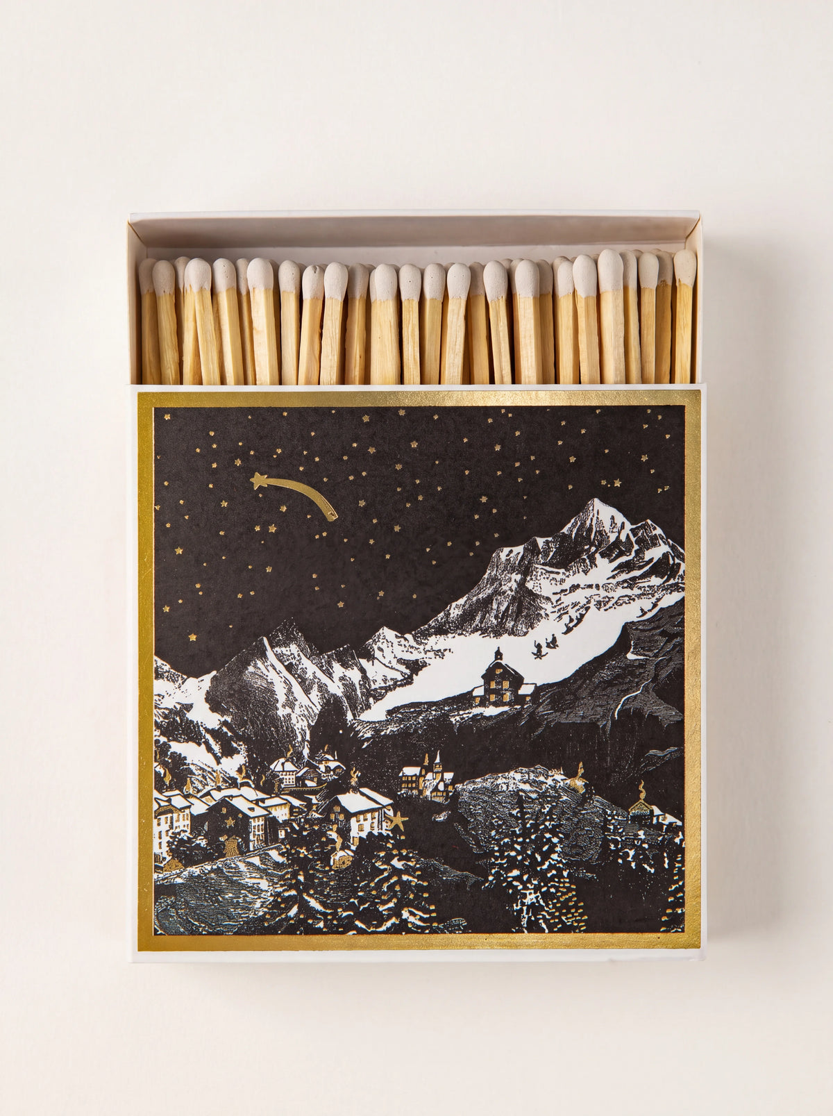 Square matchbox open to show white-tipped wooden matches, featuring an alpine winter night illustration