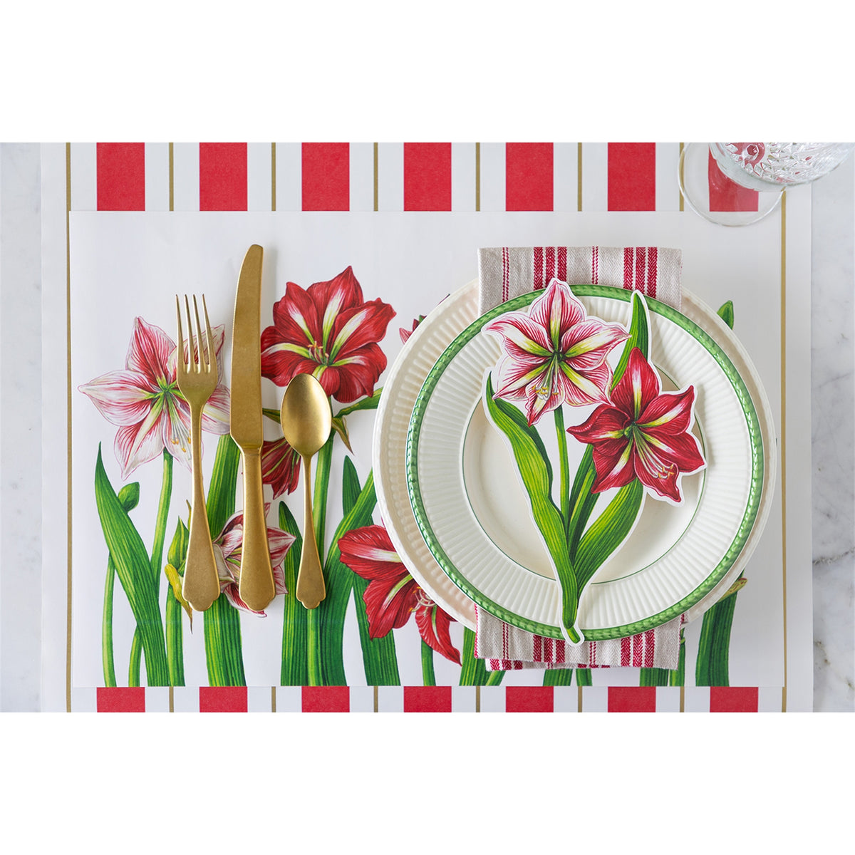 Amaryllis paper placemat laid in a place setting with a plate, napkin, and gold-tone cutlery