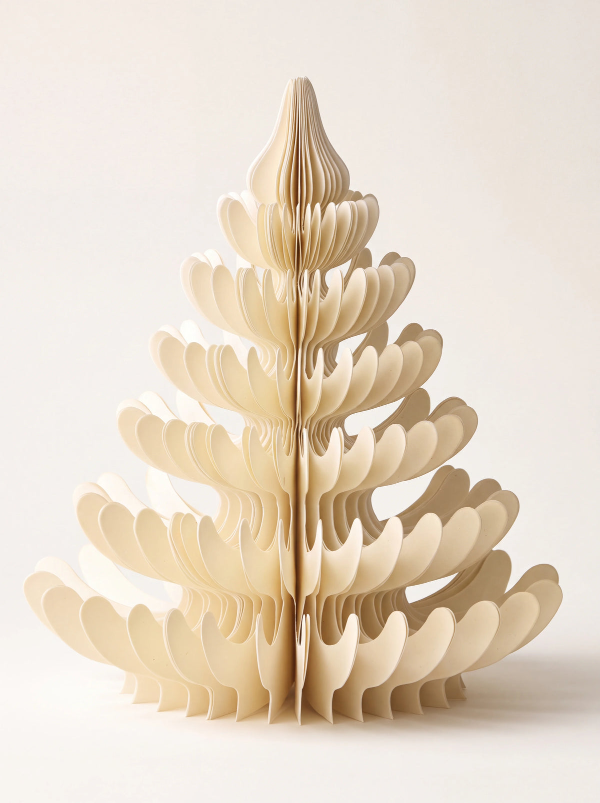 Cream paper Christmas tree decoration with tiered, curving honeycomb layers