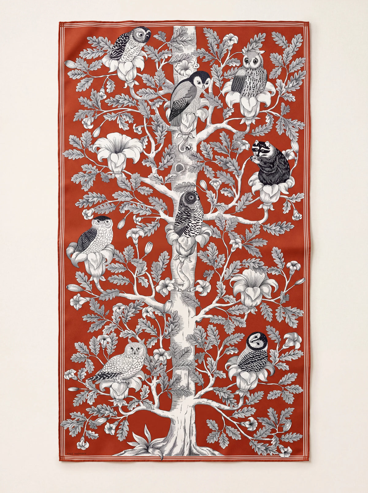 Rectangular orange wool scarf featuring a monochrome illustration of owls and a raccoon in a tree