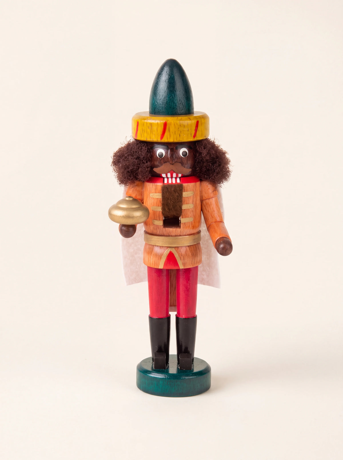 Painted wooden Balthasar nutcracker with a tall green hat, curly hair, fabric cape and a golden vessel