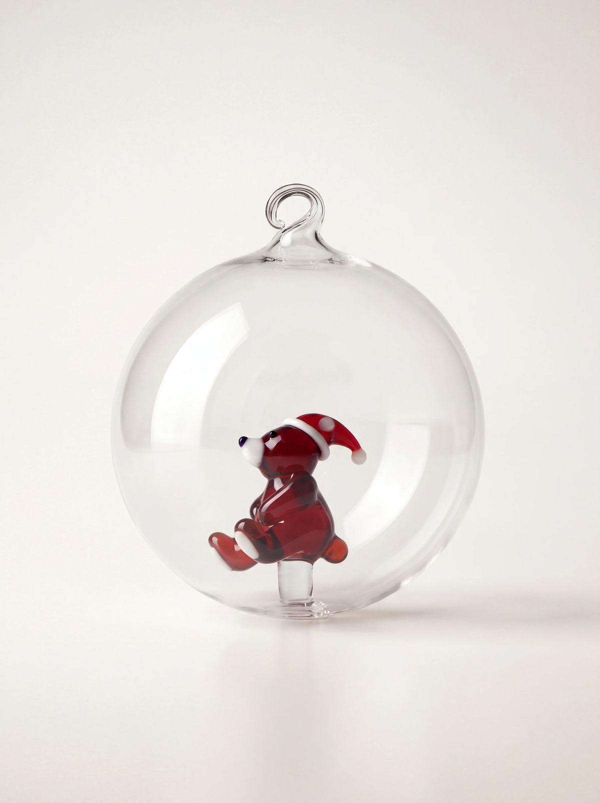 Clear glass bauble with an internal brown bear wearing a red Santa hat and a glass hanging loop at the top