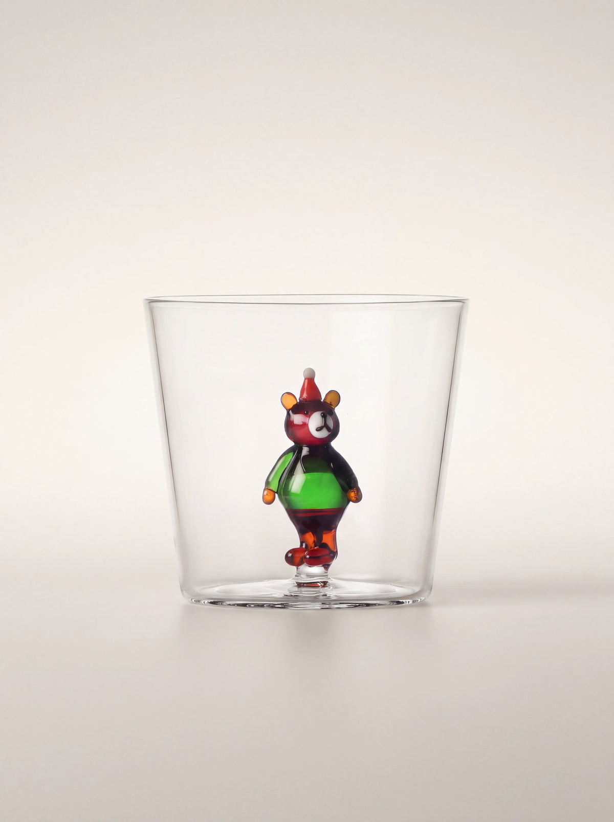 Clear borosilicate glass tumbler featuring an integrated glass bear wearing a green jumper and red hat