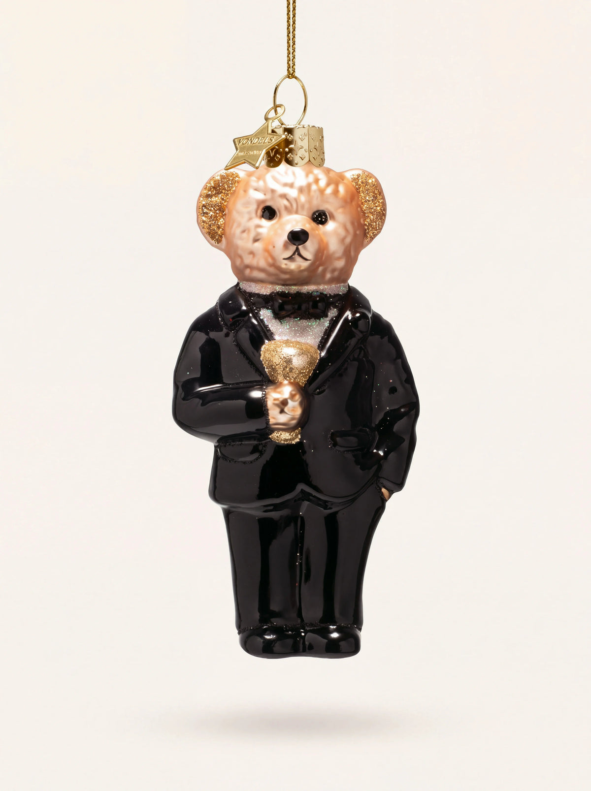 Glass bear ornament in a glossy black tuxedo holding a drink, with gold glitter details and hanging cord