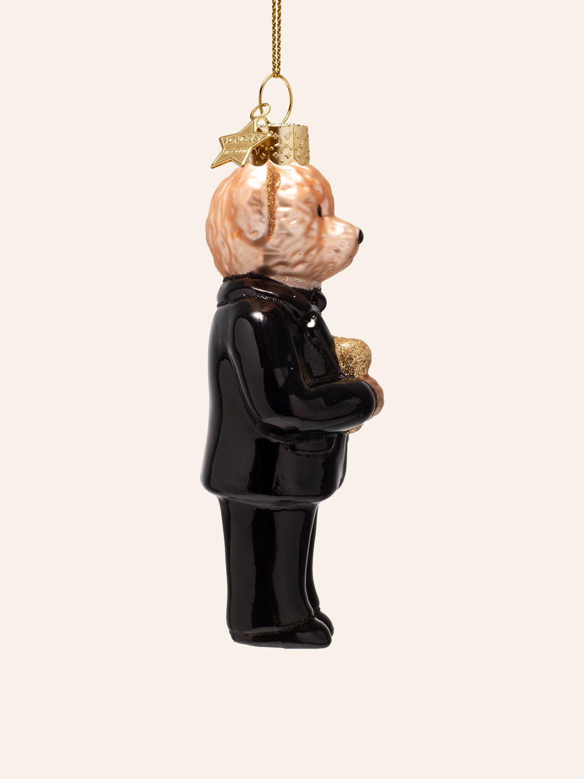 Side view of the glass bear ornament, showing its profile, glitter ear and black tuxedo jacket