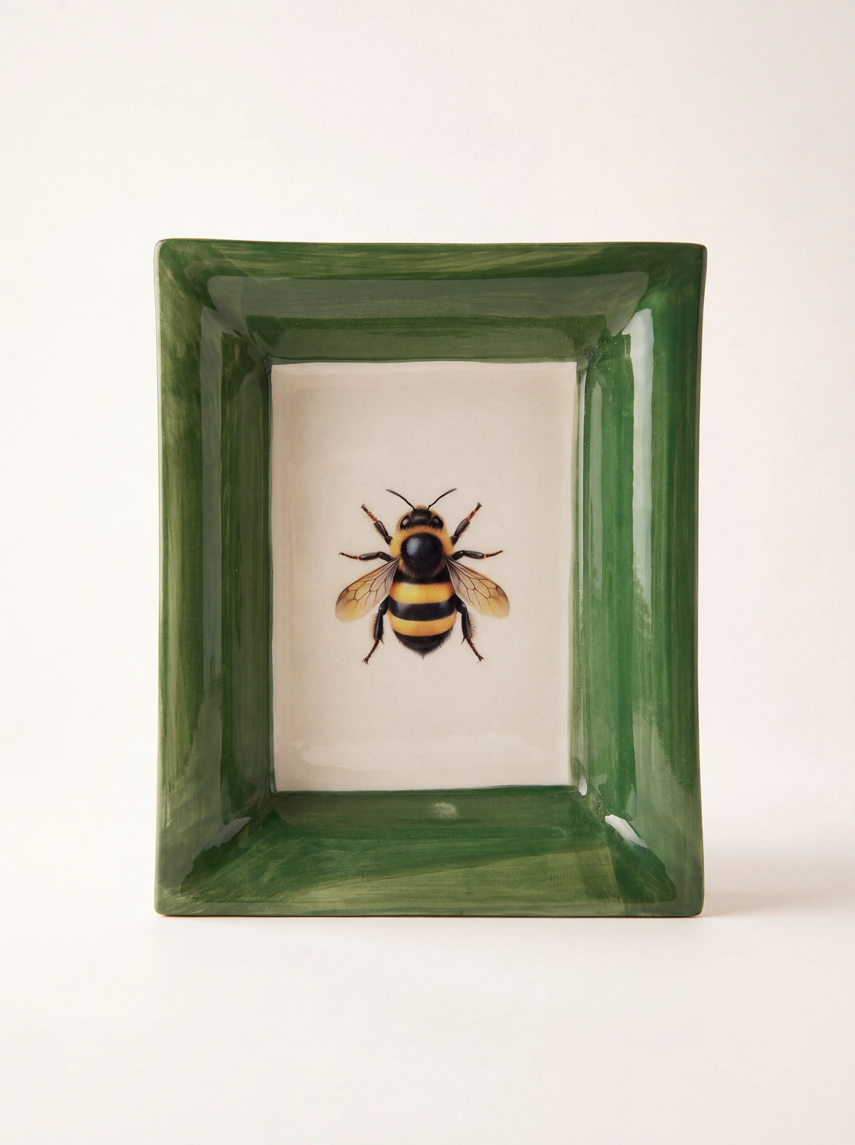 Rectangular ceramic tray with a glazed green rim and a bee motif centred on a white base