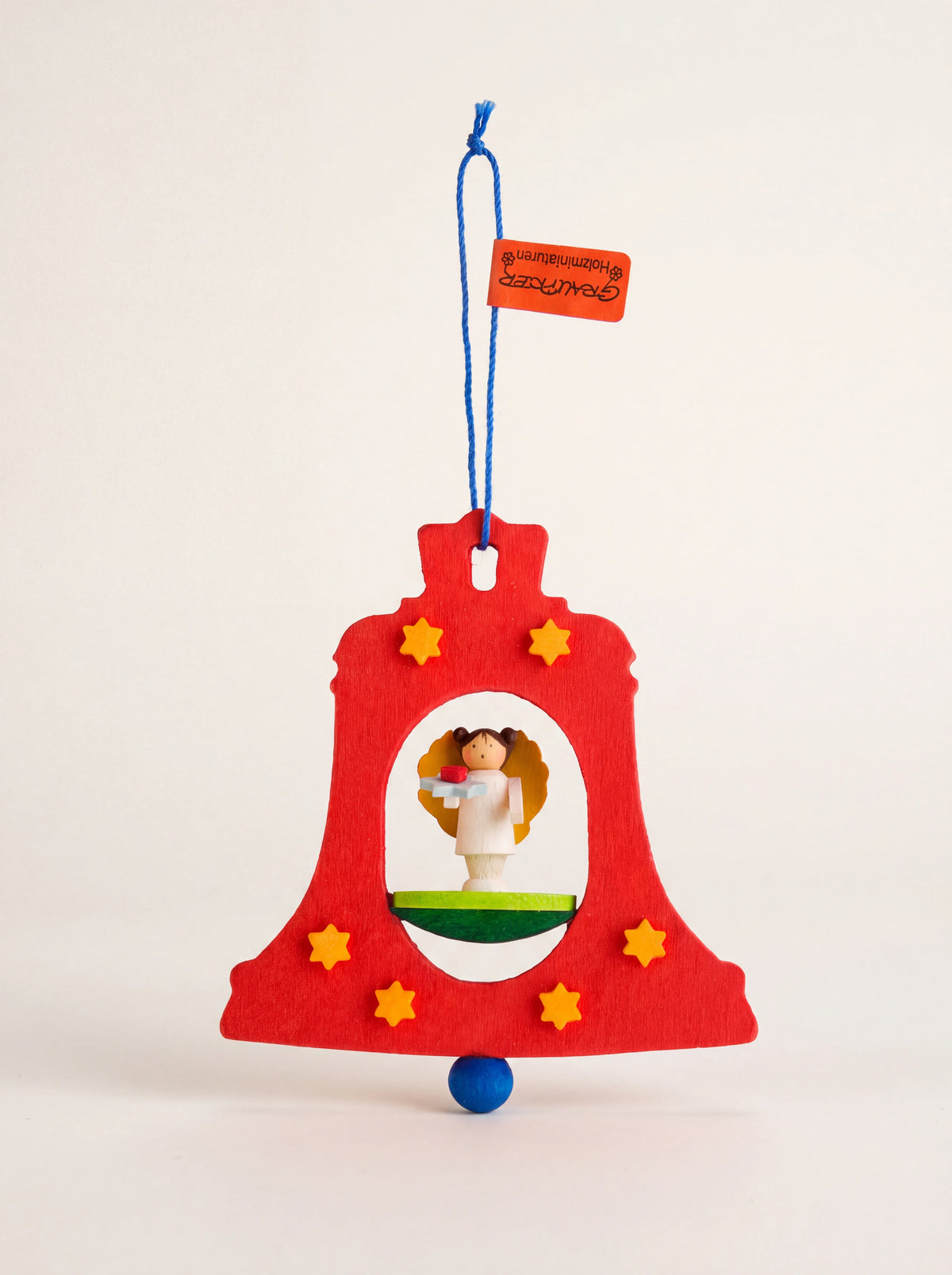 Red wooden bell ornament with yellow stars, a miniature angel figurine inside and a blue hanging cord