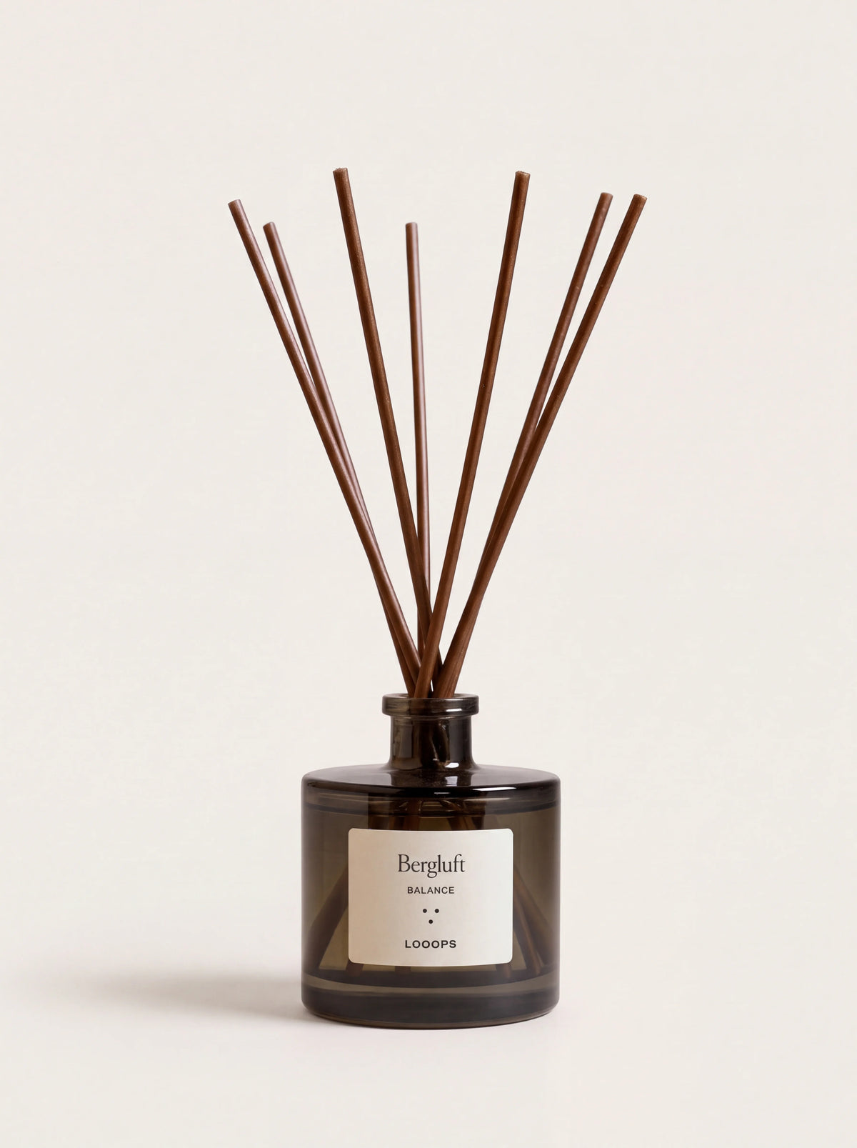 Dark cylindrical glass reed diffuser with brown paper reeds and a white label reading Bergluft Balance