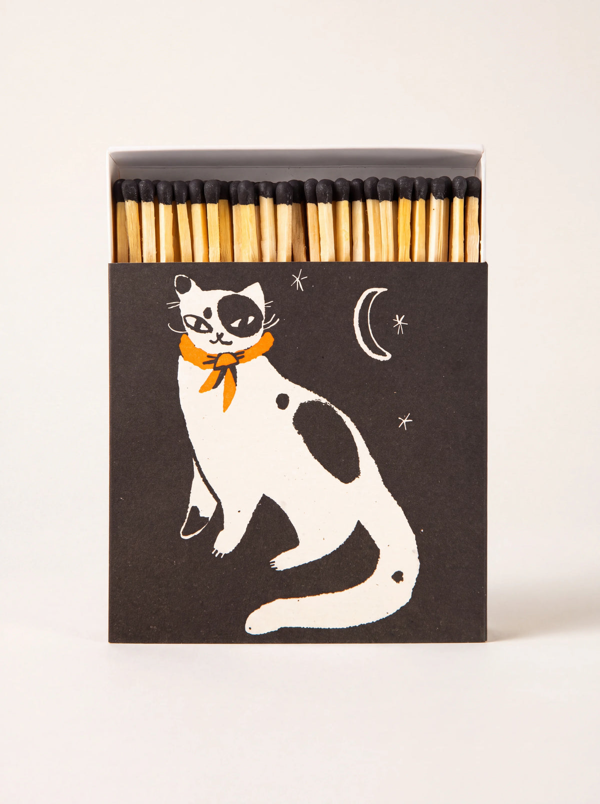 Square matchbox with an illustrated cat and crescent moon, opened to show matches with black heads