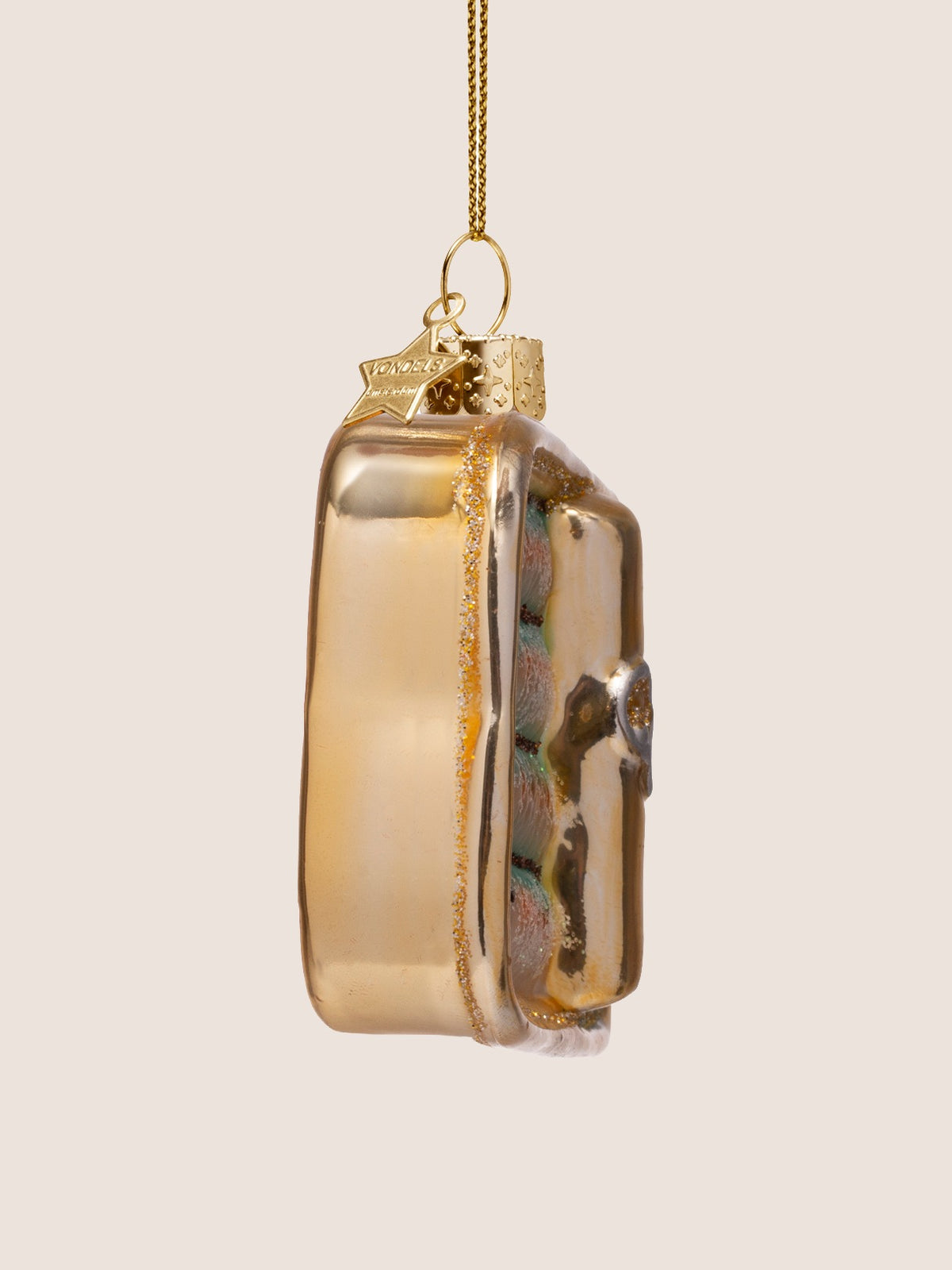 Side view of the sardine tin ornament showing its metallic gold casing and depth