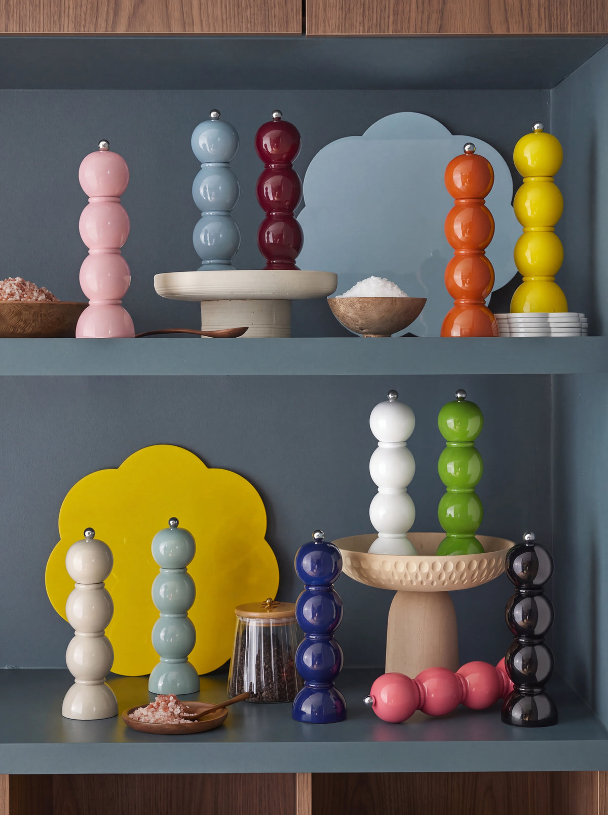 Bobbin salt and pepper mills arranged on shelves in a range of high-gloss colours