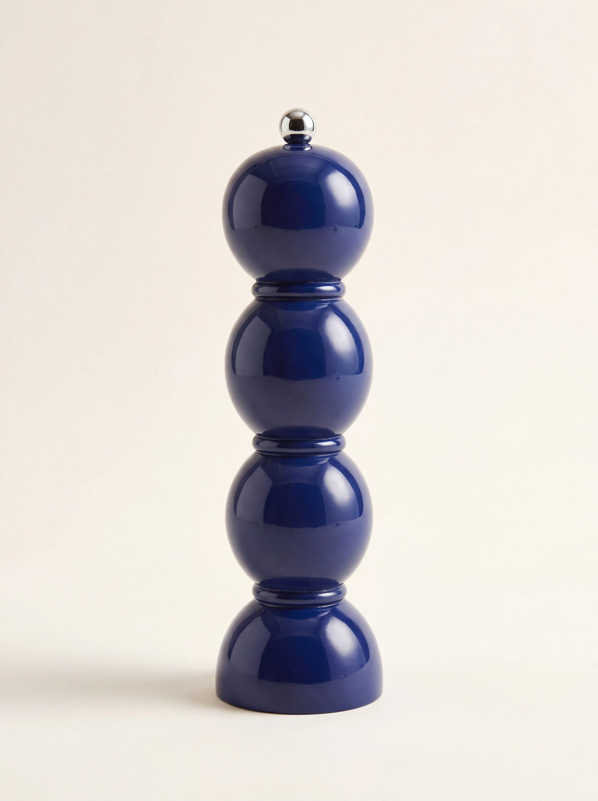Navy blue lacquered wooden grinder with a glossy bobbin silhouette and metal screw knob
