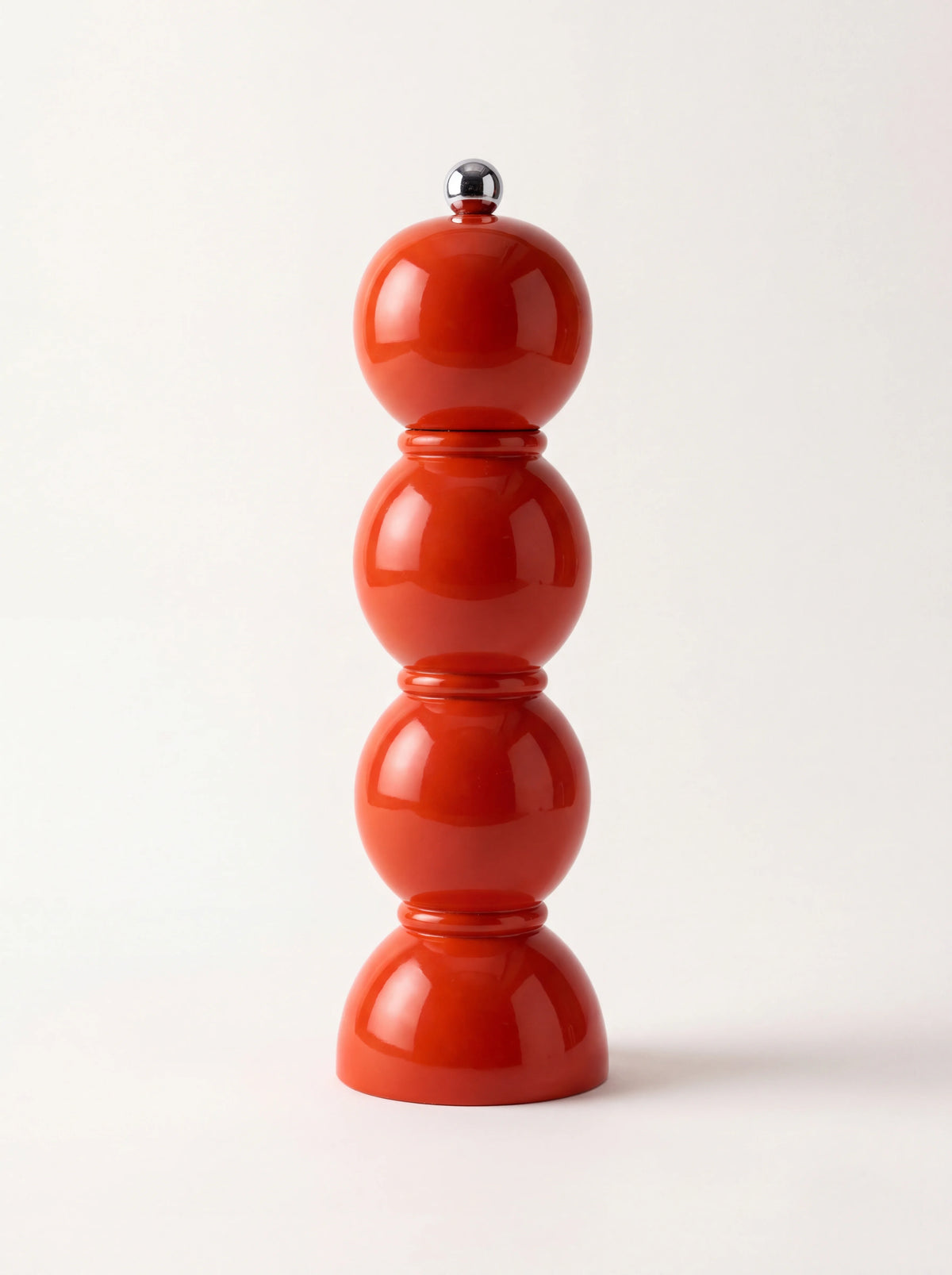 Glossy red lacquered wooden bobbin grinder with stacked spherical sections and a metal top knob