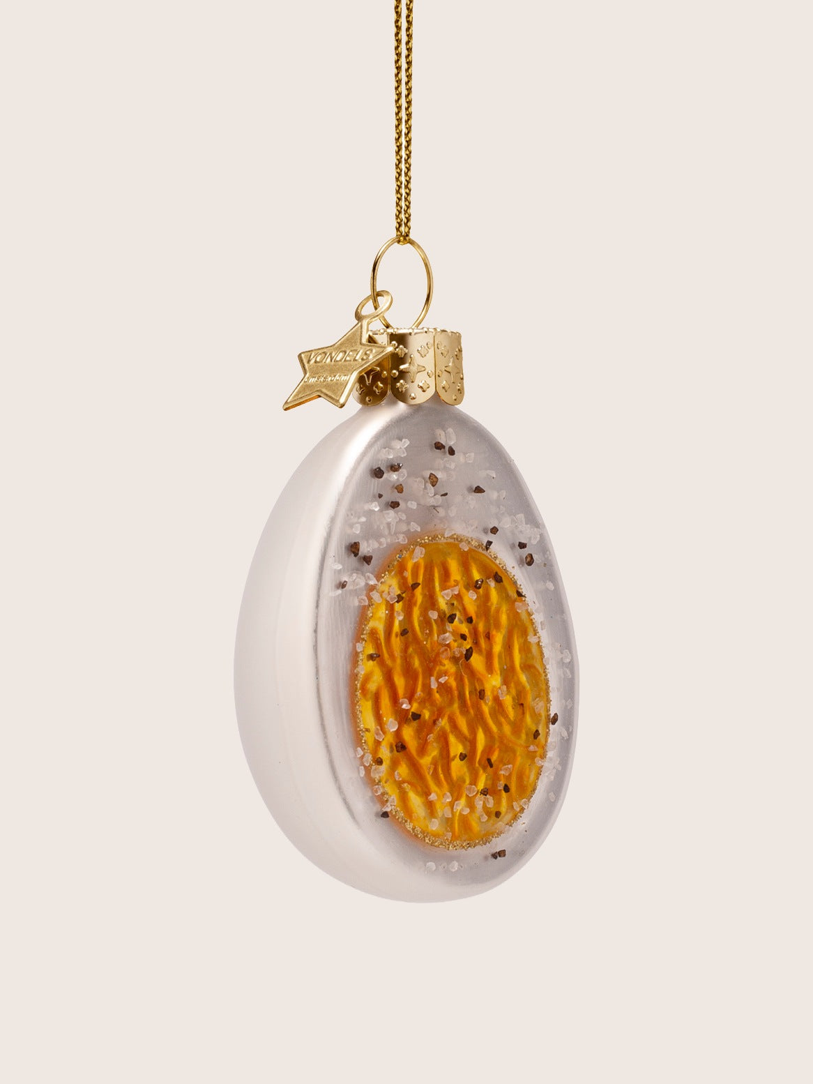 Three-quarter view showing the ornament's depth and textured glitter accents across the yolk and white