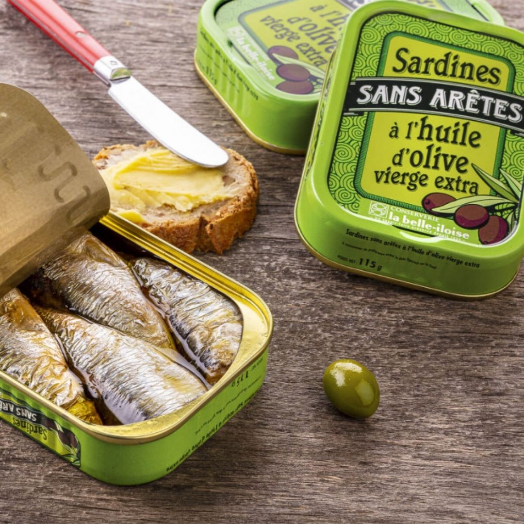 Open tin showing the boneless sardines packed in olive oil, served alongside a slice of buttered bread