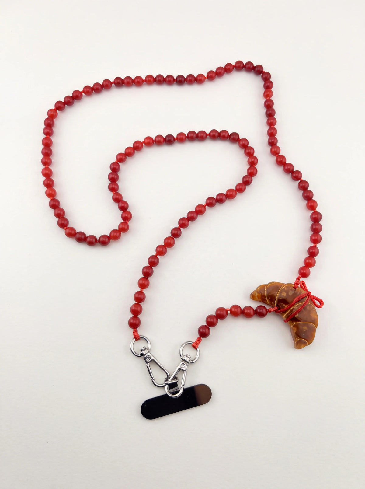 Red gemstone beaded phone chain with a croissant charm, two metal snap hooks and phone insert tab