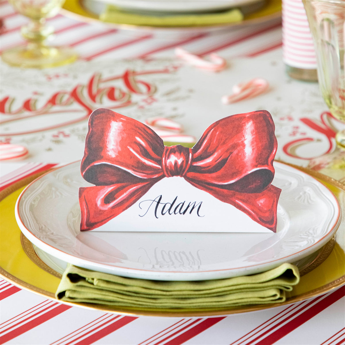 Red bow place card on a dinner plate, shown in use with the name Adam written on it