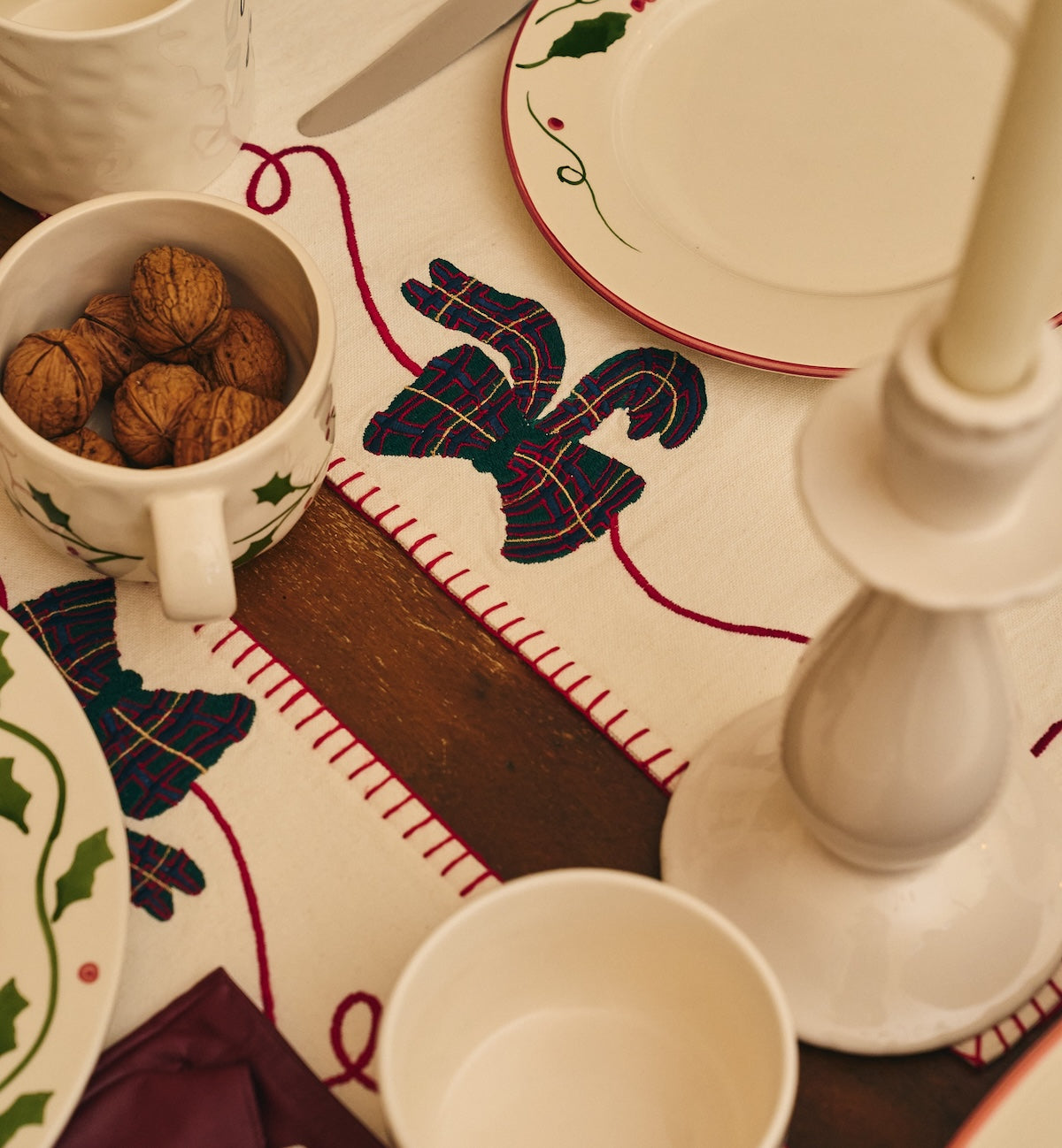 Close-up of the embroidered tartan bow detail and red blanket-stitched border on the cotton placemat