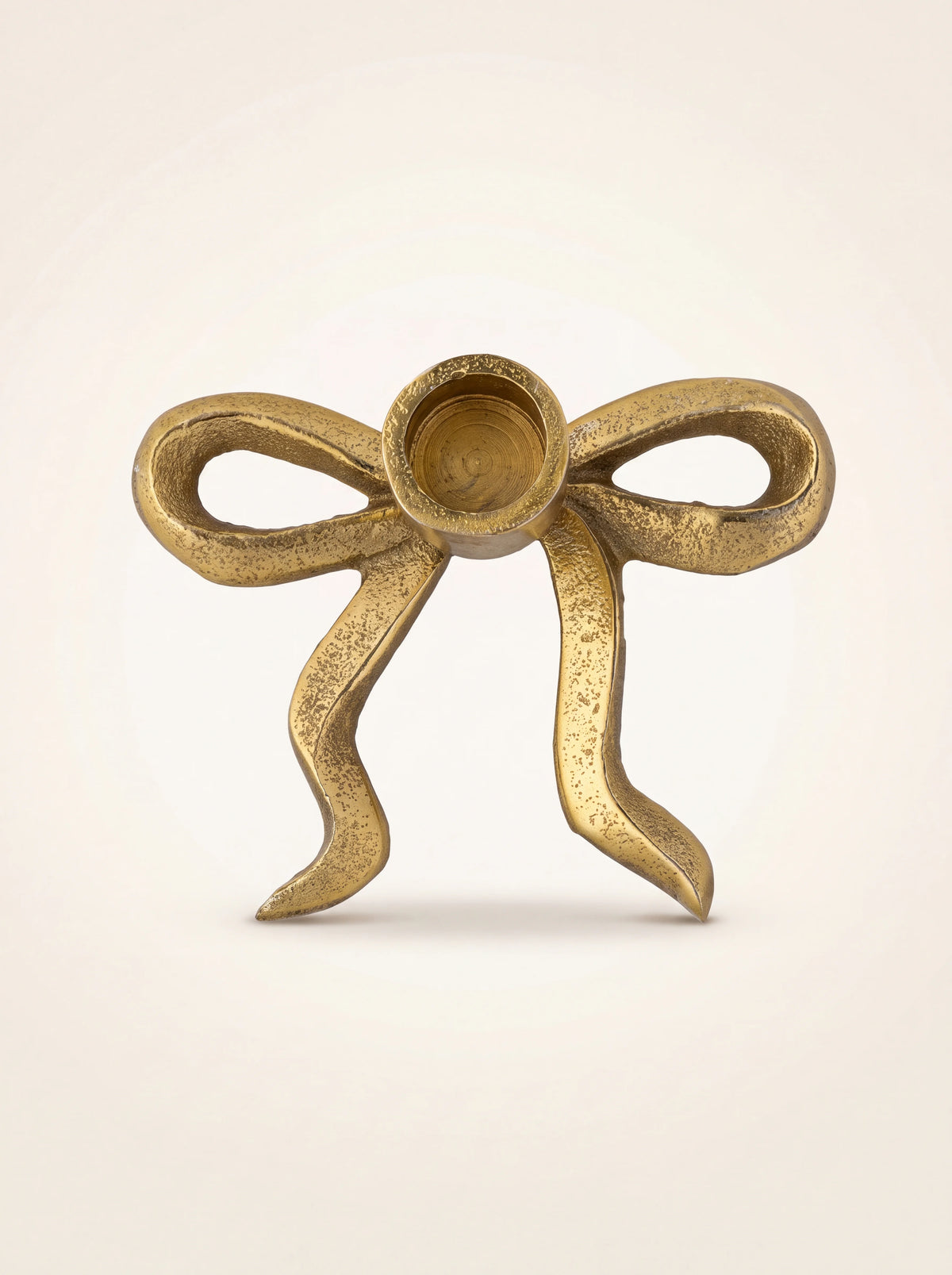 Bow-shaped candle holder seen from above, showing the ribbon loops and circular taper cup