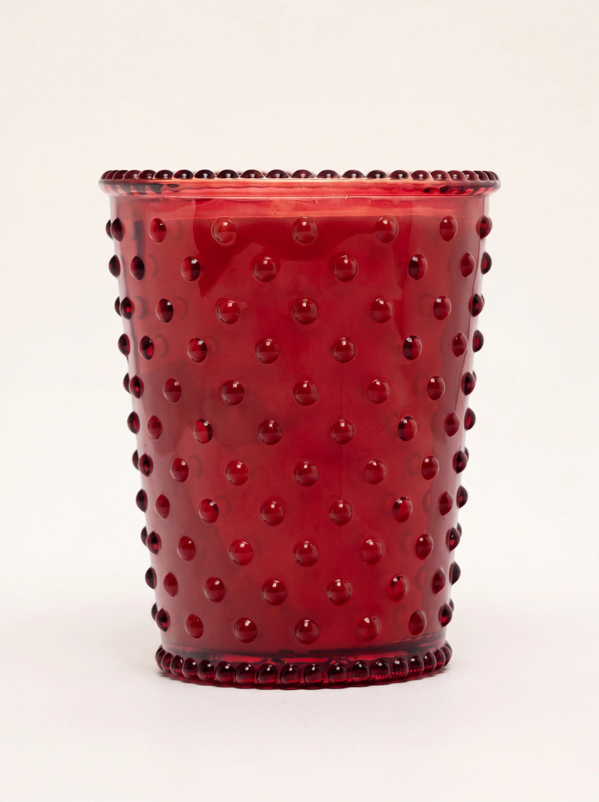 Red hobnail glass scented candle with raised studs and a beaded rim