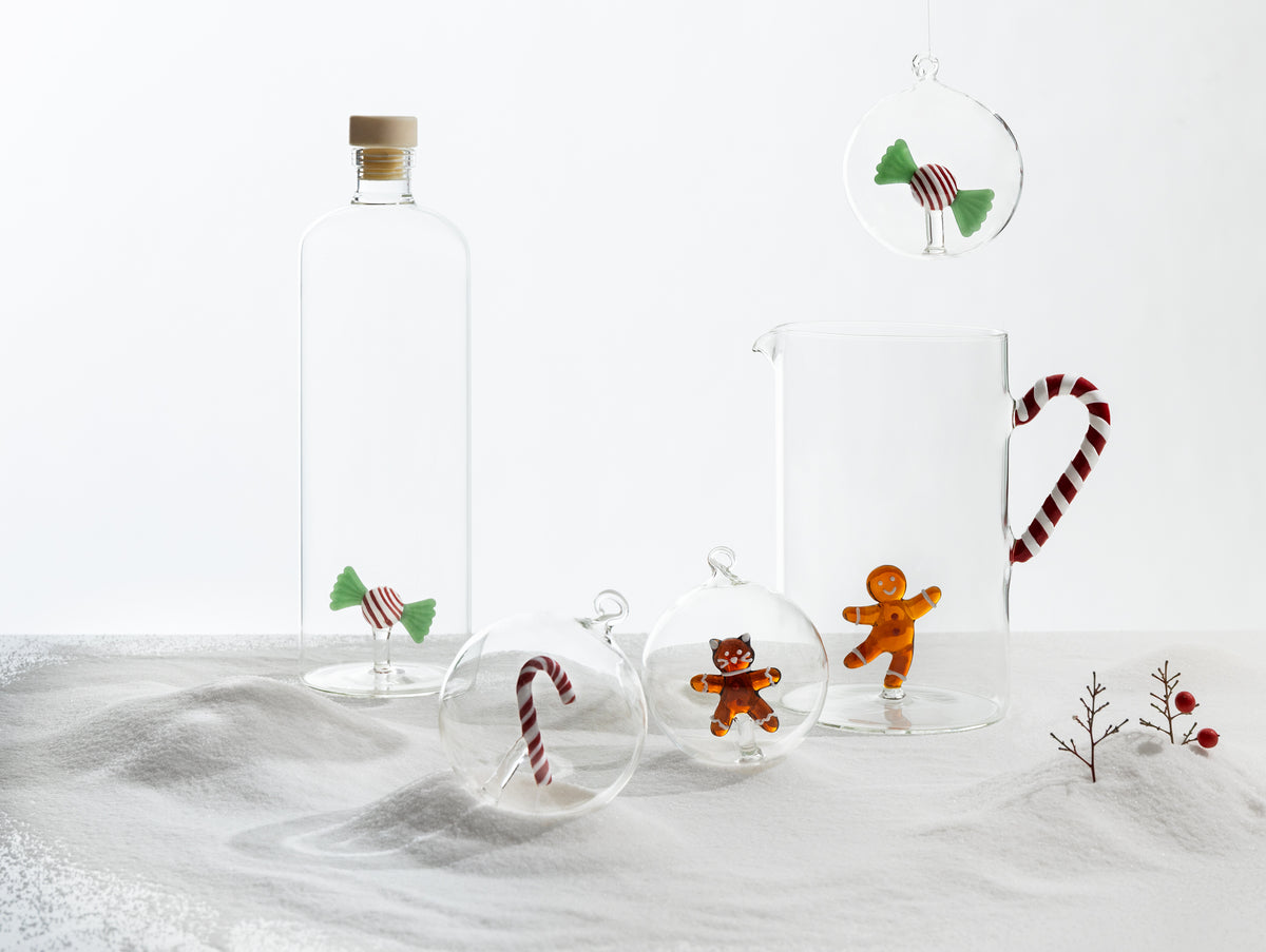 Candy glass bauble hanging suspended beside matching festive glassware and baubles