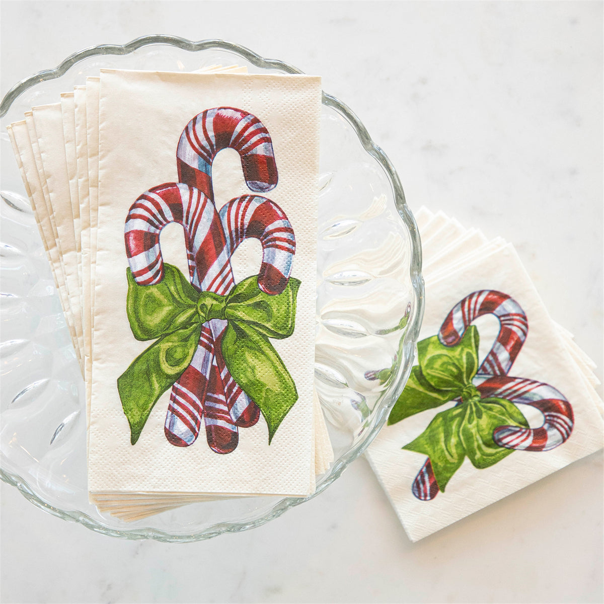 Stack of paper guest napkins showing textured paper surface, arranged in a scalloped glass dish