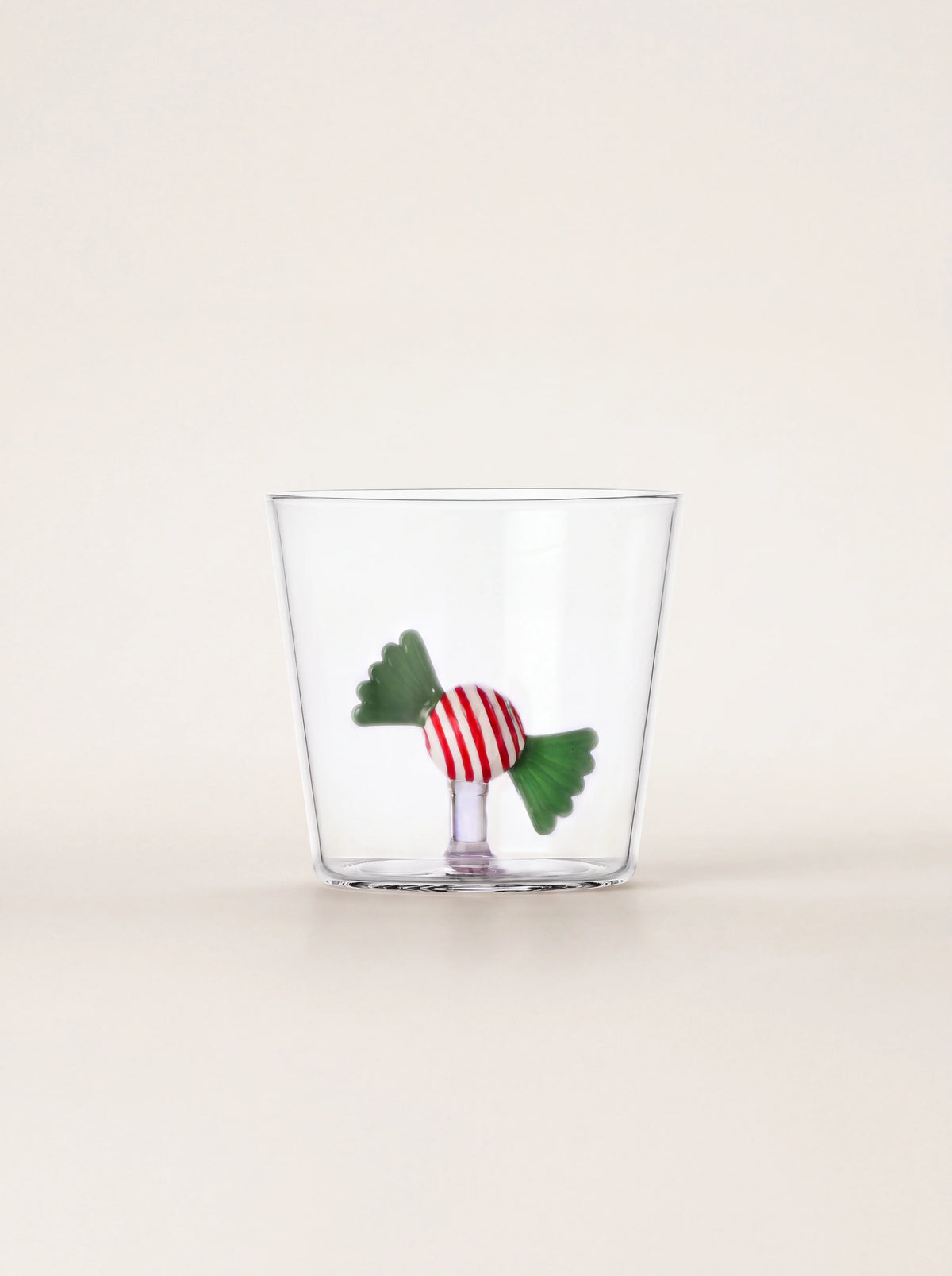 Clear borosilicate glass tumbler with a striped red and green candy figure standing inside the base