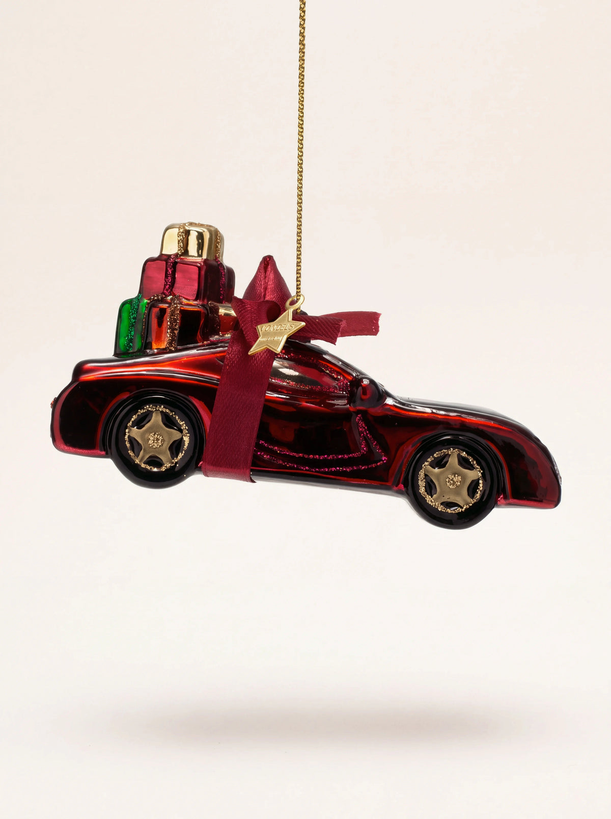 Burgundy glass sports car ornament with gift boxes tied to the roof with a ribbon bow