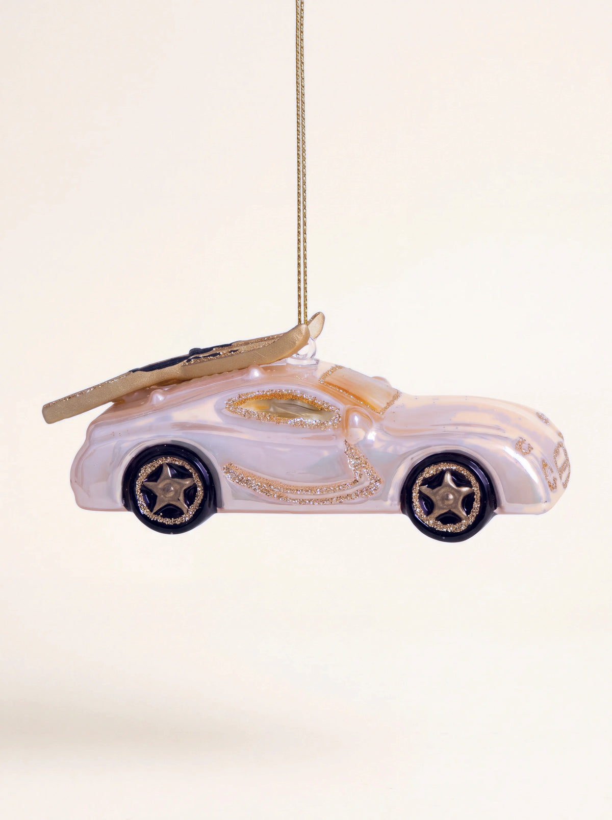 Glass sports car Christmas ornament in iridescent champagne with mounted skis, shown in side profile