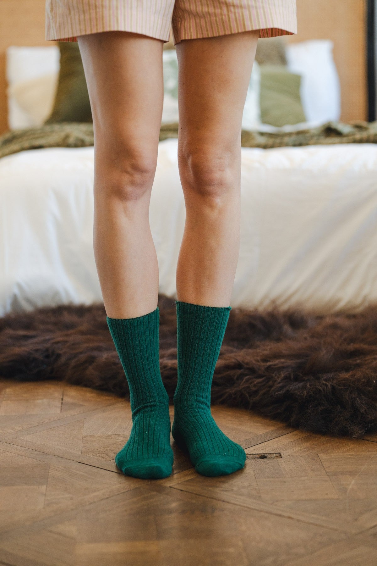 Ribbed green cashmere-blend socks worn standing, showing the mid-calf fit