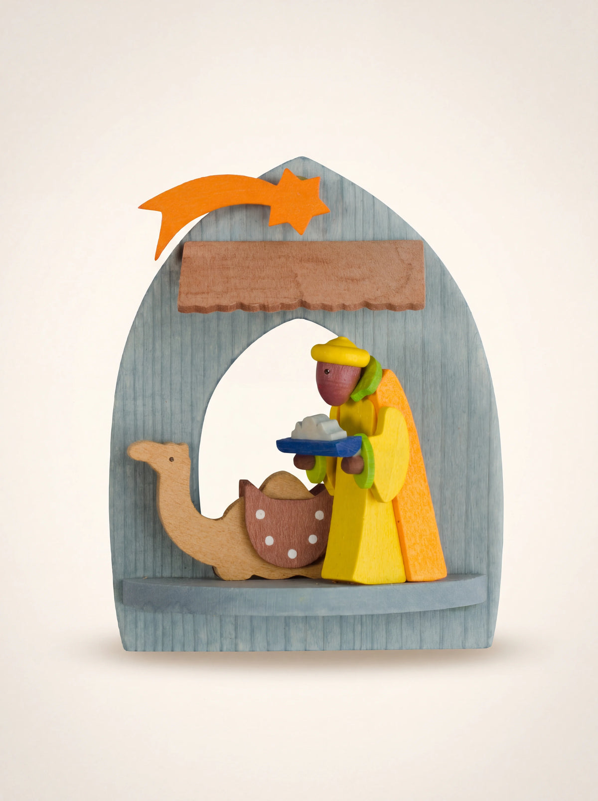 Arched wooden nativity ornament featuring Caspar holding a tray beside a resting camel under a shooting star