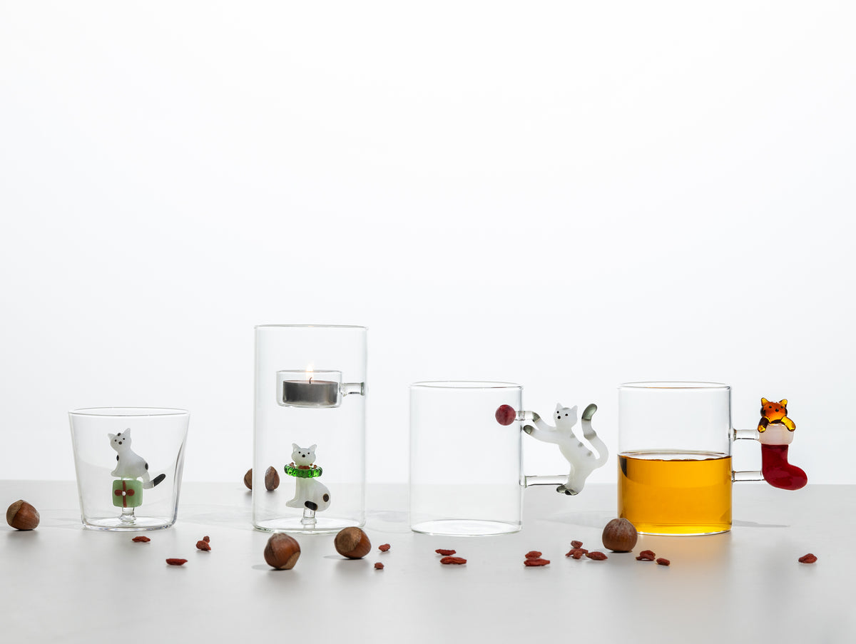 Lit tealight holder with a burning candle, shown alongside three matching cat-themed glass cups