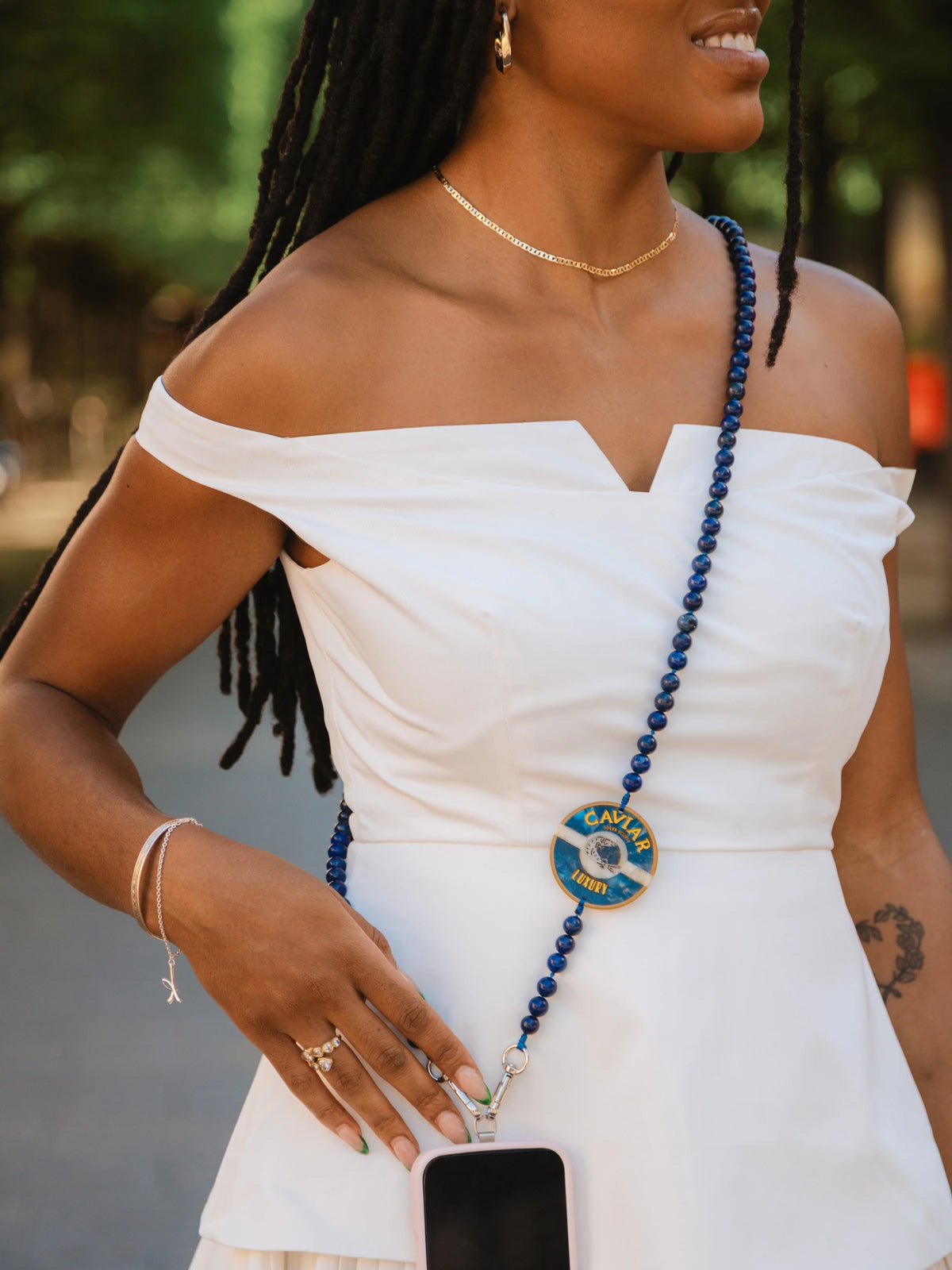 Blue gemstone phone chain worn crossbody over the shoulder and connected to a smartphone