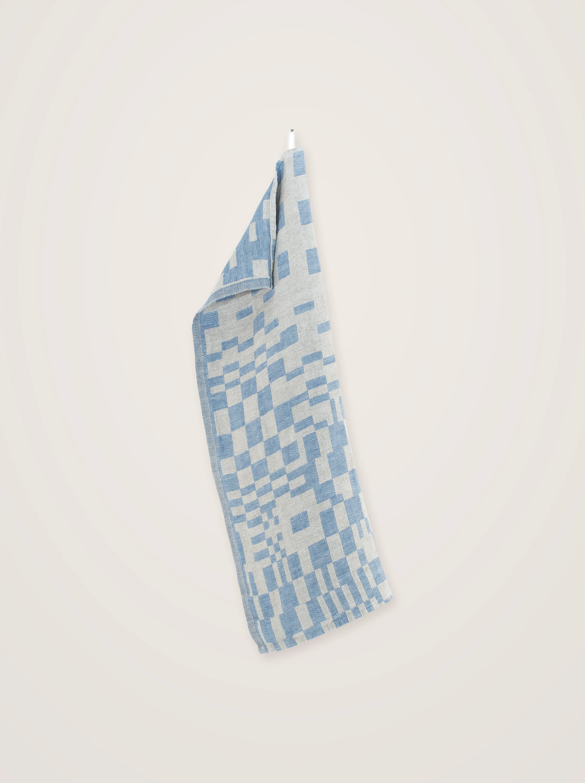 Blue and grey washed linen towel hanging by its loop, showing the full geometric check pattern