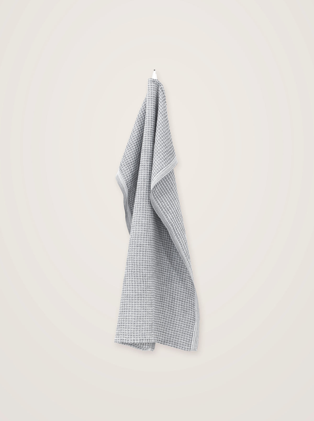 Two-tone grey and white check towel in a textured waffle weave, hanging from a white hook