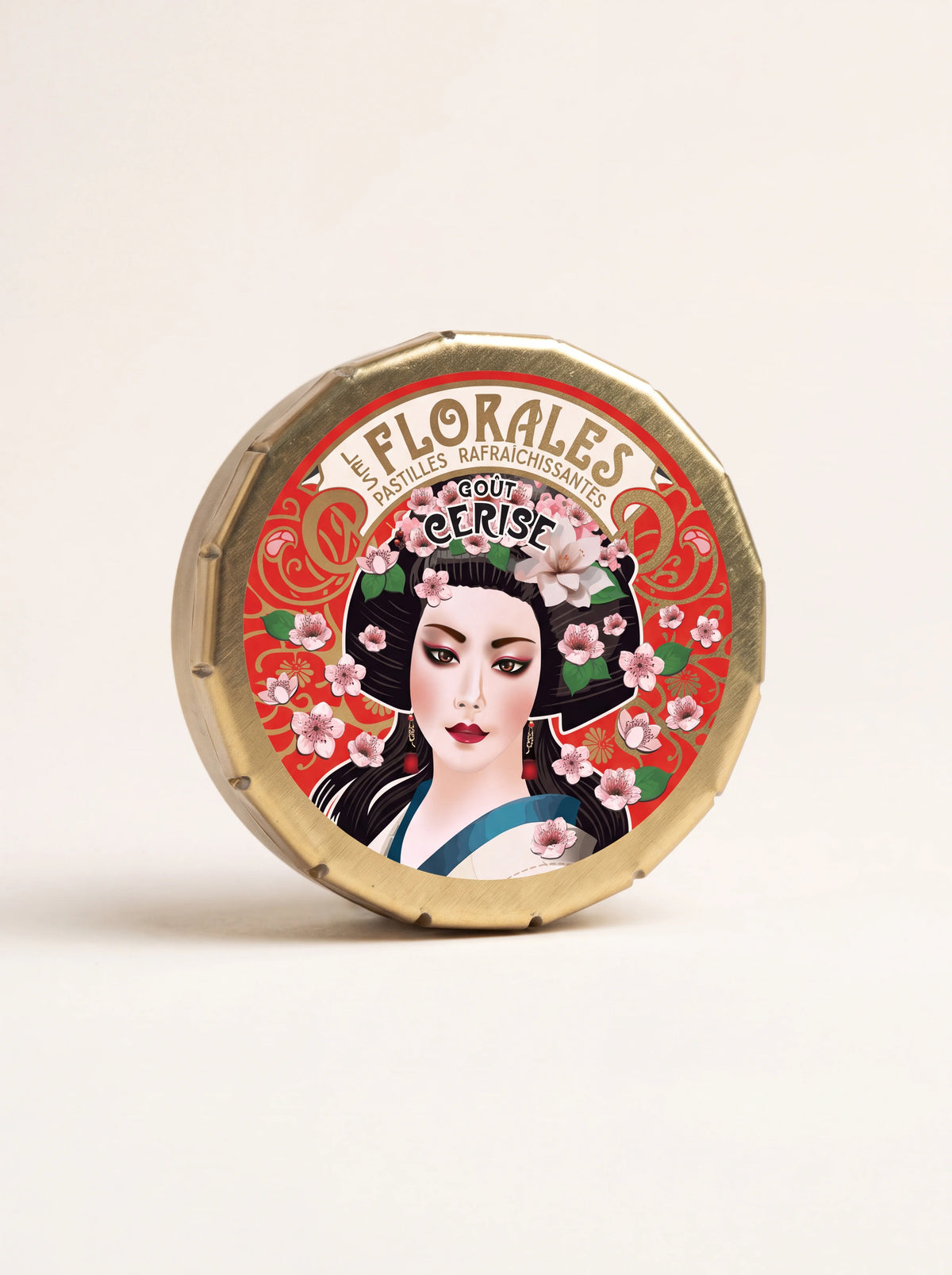 Round gold-toned metal tin featuring an illustrated geisha in cherry blossoms and Les Florales Goût Cerise