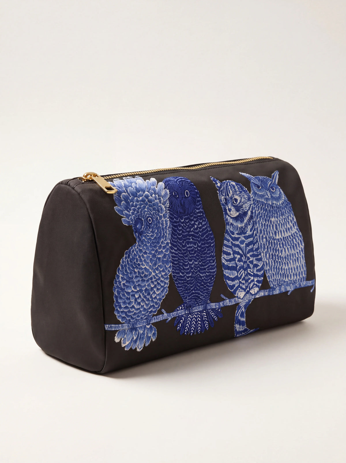 Three-quarter view showing the pouch's flat base, structured side profile and gold-tone zip pull