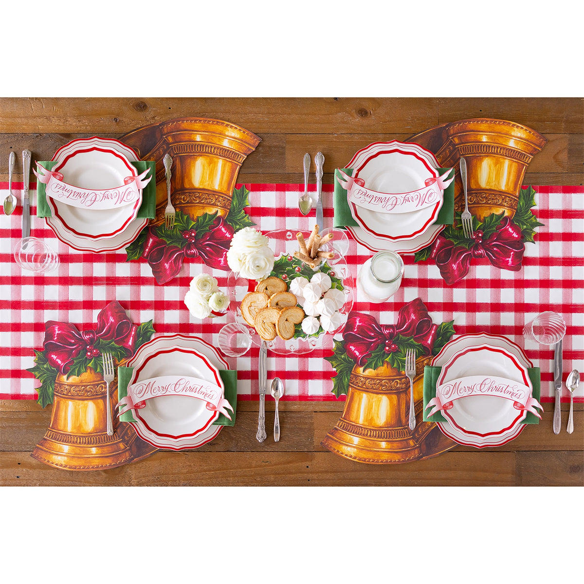 Four Christmas bell placemats set on a table over a red-and-white gingham runner with plates and cutlery