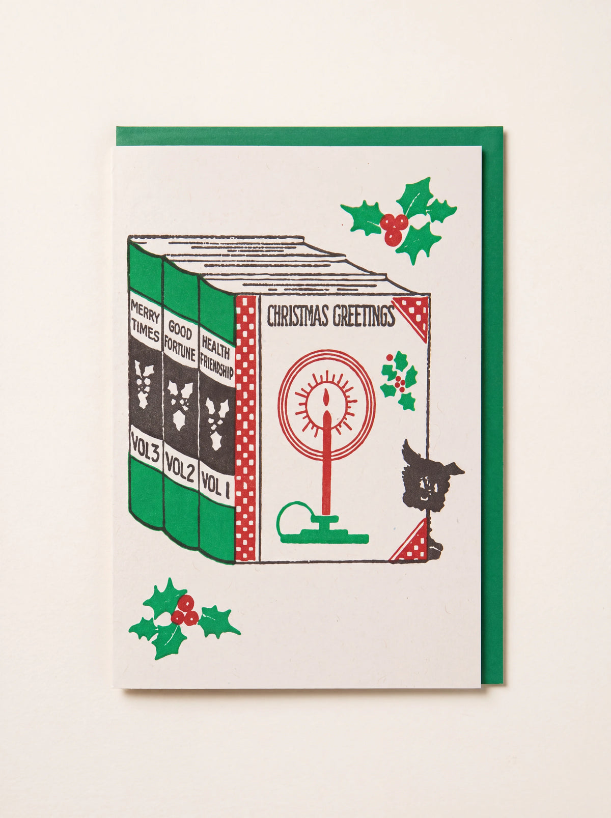 Letterpress Christmas card illustrated with festive books titled Christmas Greetings, with a green envelope
