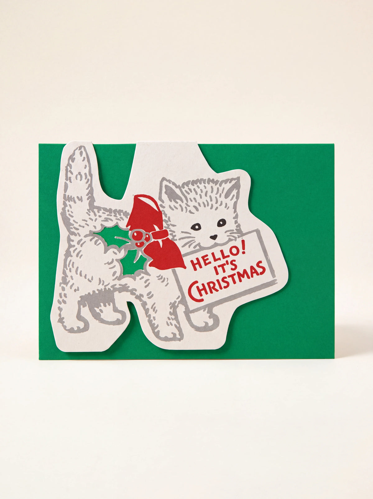 Green die-cut paper Christmas card featuring a kitten holding a sign reading 'HELLO! IT'S CHRISTMAS
