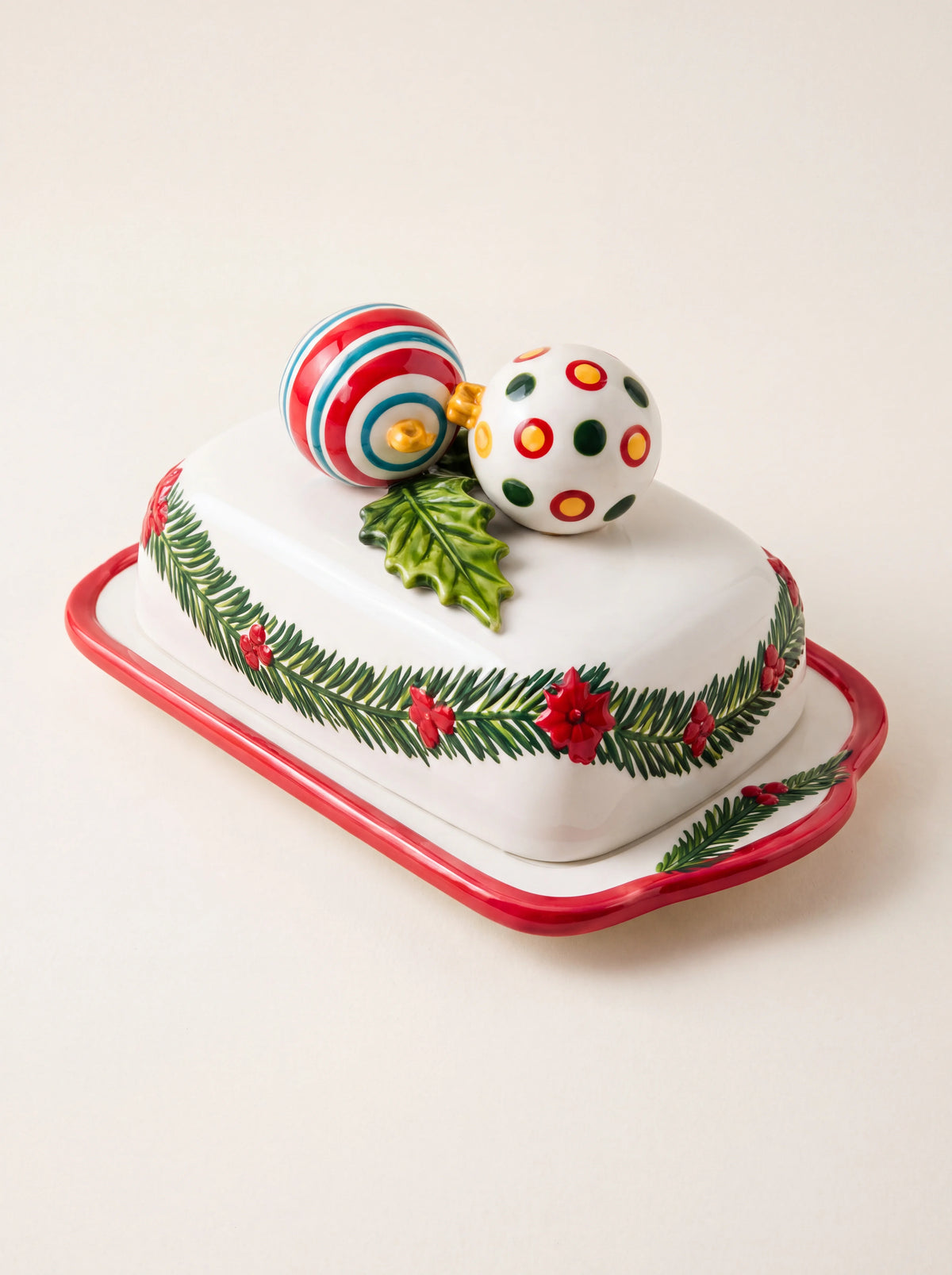 White ceramic butter dish with pine garland motifs, red rim and two sculpted baubles as a lid handle