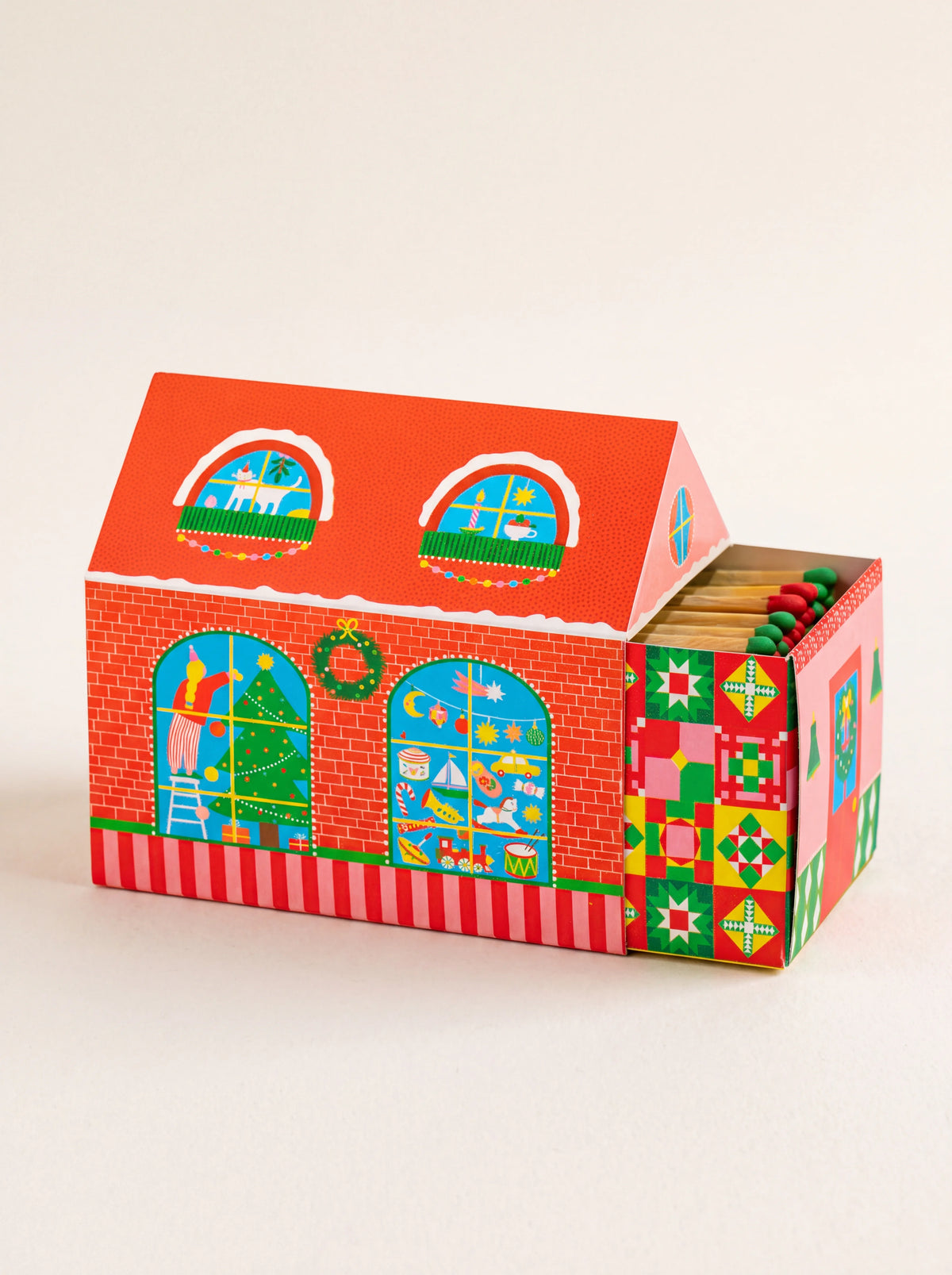 House-shaped matchbox with Christmas illustrations, its drawer open to show red- and green-tipped matches