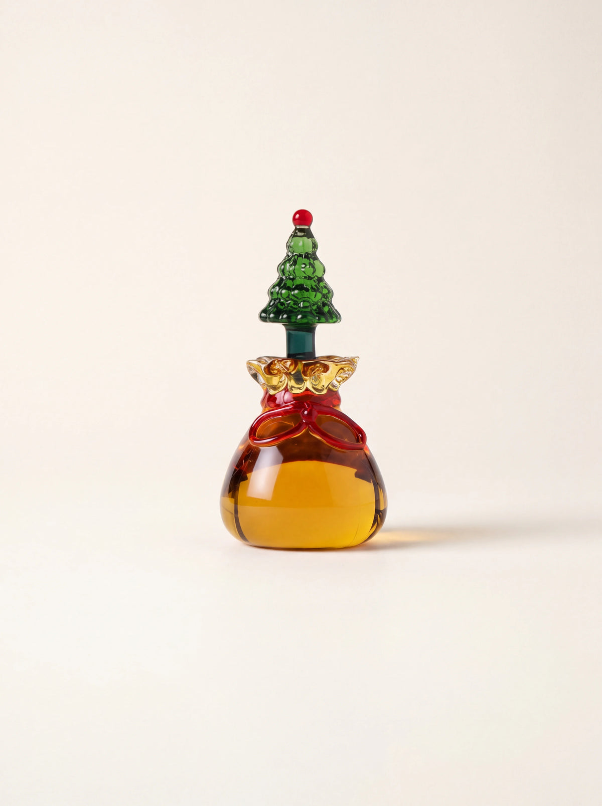Amber borosilicate glass sack place marker with a red ribbon and green Christmas tree topper