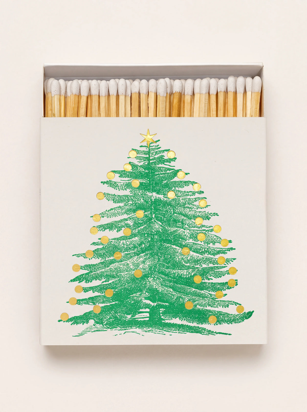 Square matchbox with green Christmas tree and gold foil accents, opened slightly to show white-tipped matches