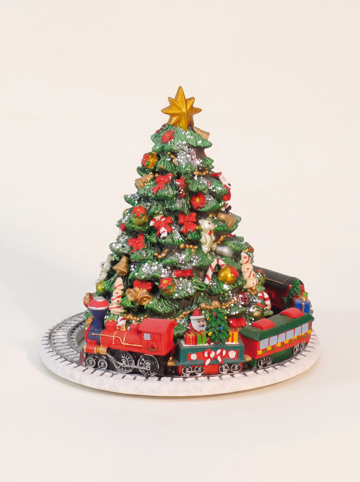 Decorated Christmas tree music box topped with a gold star and encircled by a toy train on a circular track